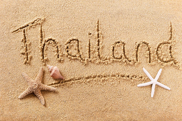 Thailand word written in sand on a sunny thai summer beach with starfish holiday vacation travel destination sign writing message photo