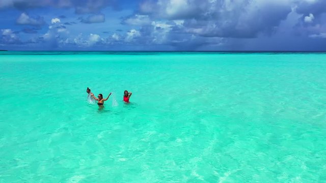 three attractive girls having fun in turquoise crystal clear water on tropical island, Thailand, aerial drone shot