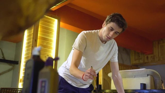 Slow motion shot of a handsome male artist uses a traditional Chinese huzhou brush inside his art studio.