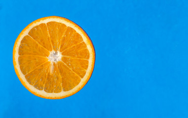 Slice of orange on blue background close-up