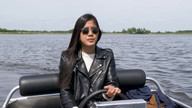 A young woman pilots a motor boat on a beautiful day.