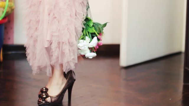 Little girl in beautiful pink dress enters the room and walk in mothers high heels