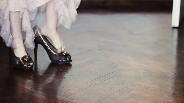 Little girl in beautiful pink dress wears her mothers high heels and walk out of the room