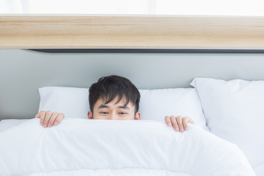 Asian man lying on bed, he slept deep in bedroom..