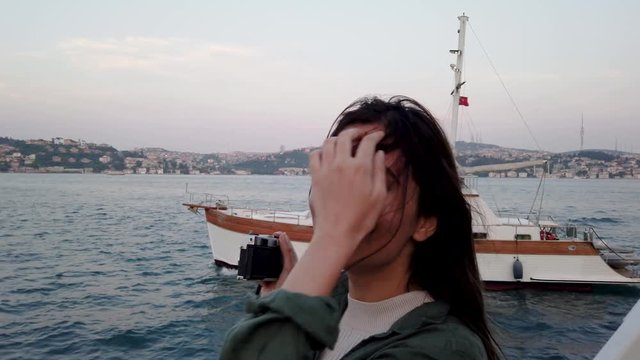 Slow motion:Beautiful young girl takes a picture while having a boat tour with view of bosphorus and landmarks in istanbul,Turkey.