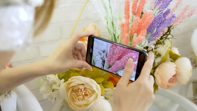 close-up. woman's hands taking mobile photo of flower arrangement in art studio, copy space