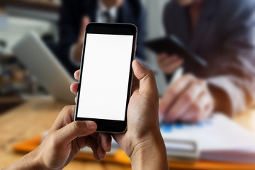 Fototapeta na wymiar Hand holding white smart phone with blank white screen in office.