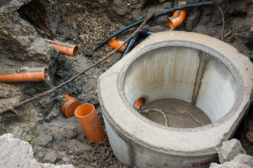 Building concrete sewage tank, flowing water trough orange pipes  in the city.