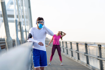 Couple exercise on the bridge at the end of day with headphones on head