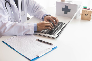 Close up male doctor or medical student using mobile smart phone working on laptop computer in hospital with copy space.