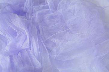 Fototapeta premium Textile and textural concept - close up of a crumpled veil of lilac wavy fabric background with copy space for text or image
