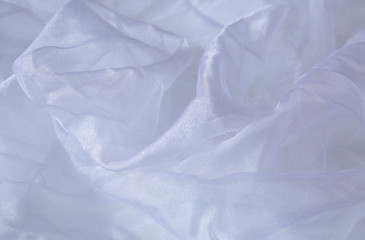Textile and textural concept - close up of crumpled silk lilac wavy fabric background with copy space for text or image