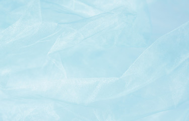 Textile and textural concept - close up of crumpled blue veil wavy fabric background with copy space for text or image