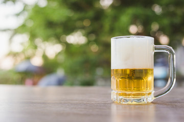 Beer in glass on wooden table with natural background with bokeh