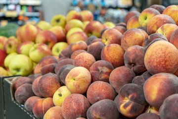 Close-up of fresh, ripe peaches on the store counter in front of fruits