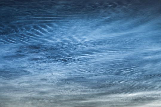 Close up of NLC: noctilucent clouds. Beautiful waves and ripples of silvery blue night shining clouds around midnight.