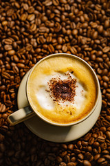 Cappuccino cup on roasted coffee beans.