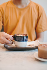 Asian man on yellow T-shirt, Selected focus,hand holding the glass hot coffee in the cafe or restaurant