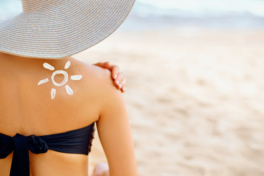 Woman Putting Sunblock Lotion On Shoulder Before Tanning During Summer Holiday On Beach Vacation Resort