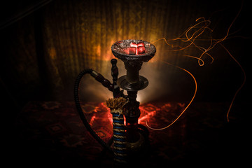 Hookah hot coals on shisha bowl on dark foggy background. Stylish oriental shisha.