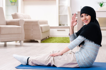 Young woman in hijab doing exercises at home 