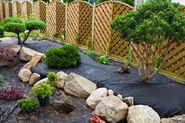 Making new home garden decorations, planting evergreen trees and creating decorative stone bed.
