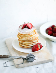 breakfast a stack of lush pancakes with strawberries on a white plate on a light background