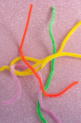 Neon colored pipe cleaners on a pink background. Messy and crumpled concept, metaphor.