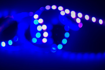Violet and blue neon blurry swirl of bokeh led lights on black. Abstract night party background