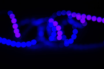 Blurred duotone neon curls led lights on black. Abstract night party background