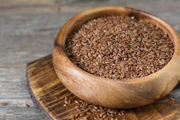 Flax seeds in a wooden bowl on a gray wooden table. Rustic style