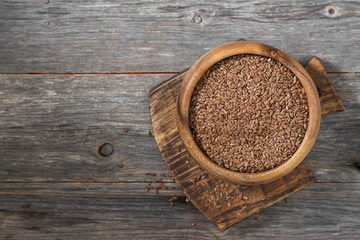 Flax seeds in a wooden bowl on a gray wooden table. Rustic style