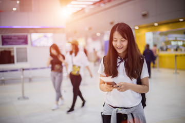 Travel Concept, Young woman tourist nternational airport with luggage, standing near the flight information display, She is waiting for check-in time.