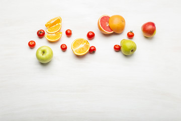 Different fruit orange slices in pears and apples lie near red tomatoes on a white table with copy space. Vegan food concept. Advertising space