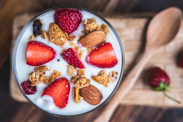 Health concept - Yogurt and strawberries on a wooden table, Homemade granola. Top view.