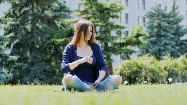 Mosquitoes and midges attack and bite the girl who rests in the park sitting on the grass