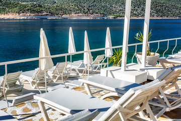Luxury beach in a beautiful bay with white deck chairs. Magnificent views of the sea and mountains on a sunny day.
