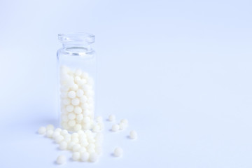 Close up homeopathic globules and glass bottle on blue background. Alternative Homeopathy medicine herbs, healtcare and pills concept. Flatlay. copyspace for text