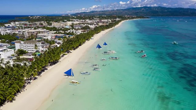 Crowds of people and boats around a beautiful, busy tropical beach (White Beach, Boracay, Philippines)