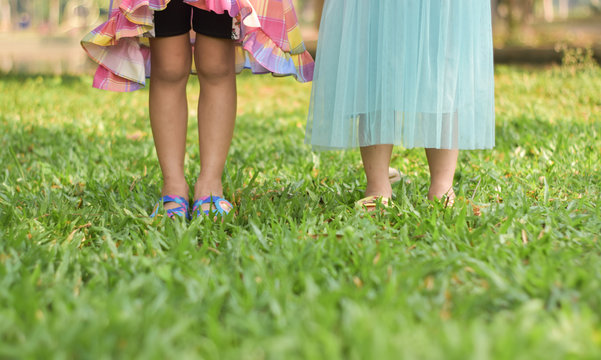 Feet of two little girls on grass in summer.