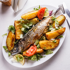 Baked stuffed fish with potatoes on the plate