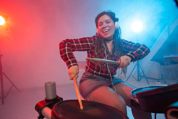 Hobby, music and people concept - Excited woman playing the electronic drum set