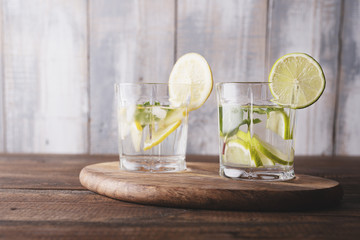 Morning detox. refreshing water with lemon, mint and ice on wooden background