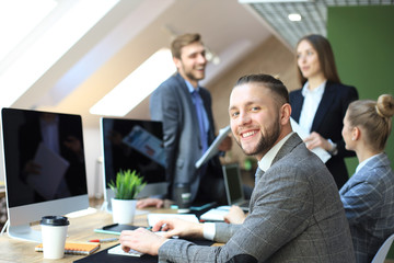 Businessman with colleagues in the background in office.