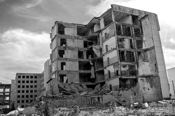 The remains of a destroyed concrete building against the sky. Black and white. Background