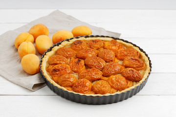 Homemade apricot pie with fresh fruits on white wooden table. Shallow focus.