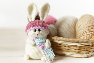 Knitted toy rabbit Handmade on wooden table. Crochet stuffed animals.