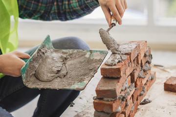 Engineer concept - Close up hand worker with wall plastering tools to repair the house, Building construction and extension with concrete plastering and brick walls.