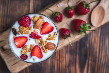 Health concept - Yogurt and strawberries on a wooden table, Homemade granola. Top view.
