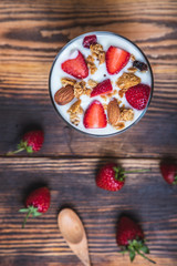 Health concept - Yogurt and strawberries on a wooden table, Homemade granola. Top view.